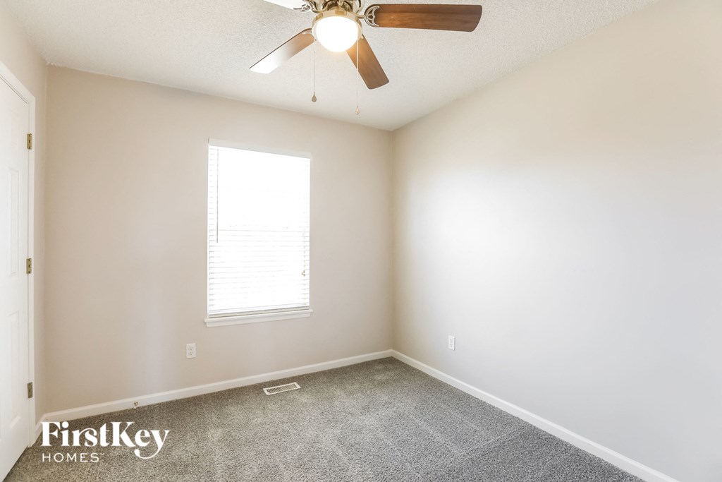 an empty room with a ceiling fan and a window