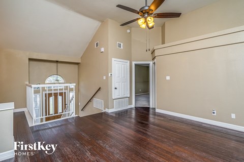 the living room of an empty house with a ceiling fan