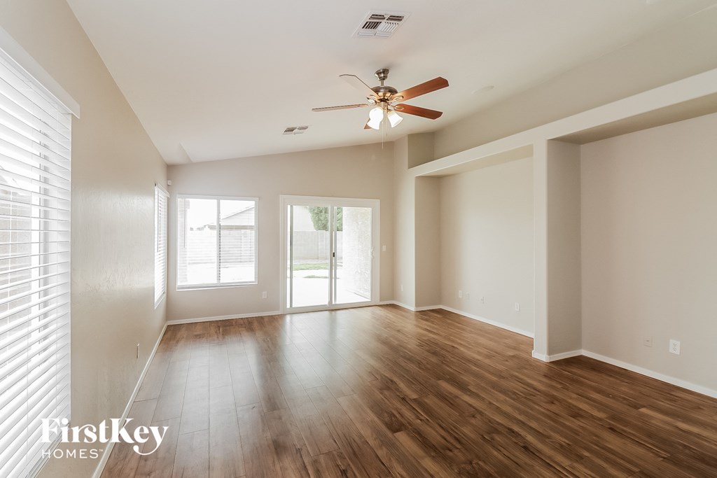 A spacious room with wooden floors and a ceiling fan.