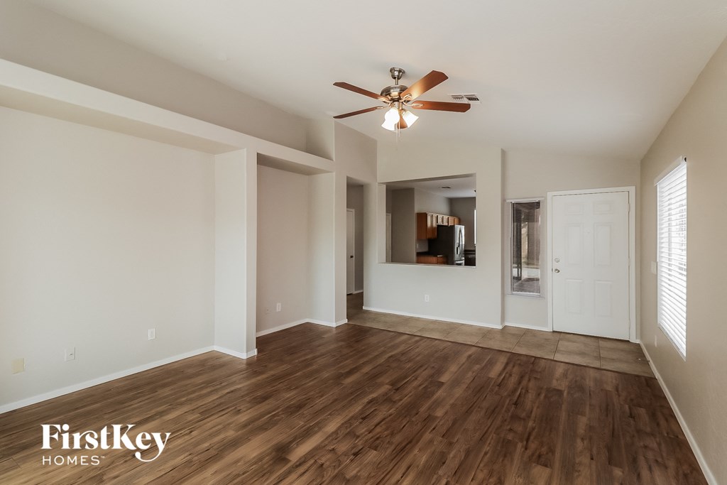 A room with a ceiling fan and wooden floors.