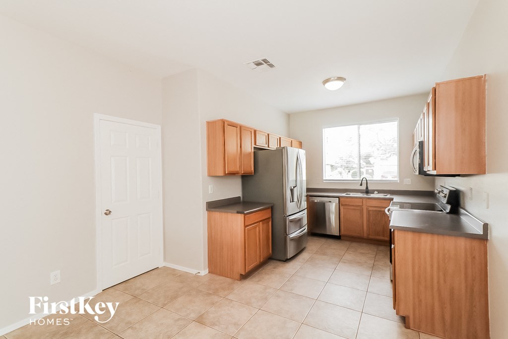 A kitchen with wooden cabinets and a tiled floor.