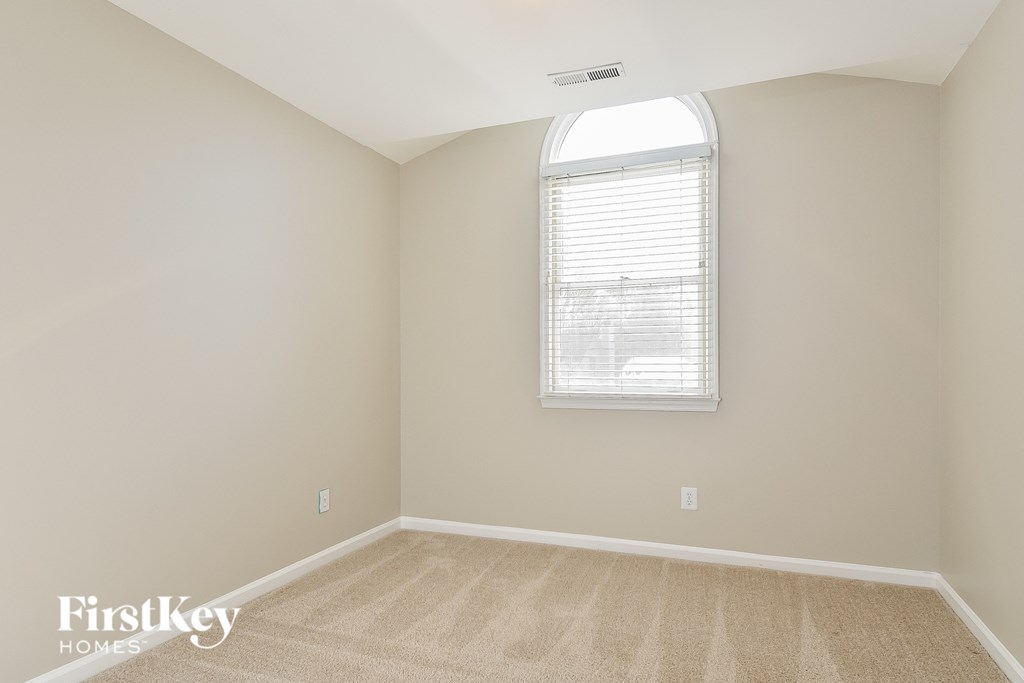 a bedroom with a window and a carpeted floor