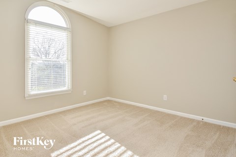 a bedroom with a large window and beige carpet