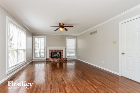 A spacious room with a fireplace and a ceiling fan.
