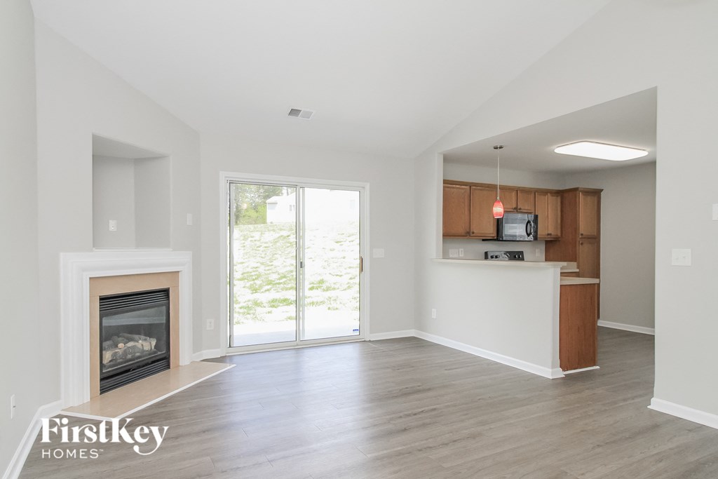 an empty living room with a fireplace and a kitchen