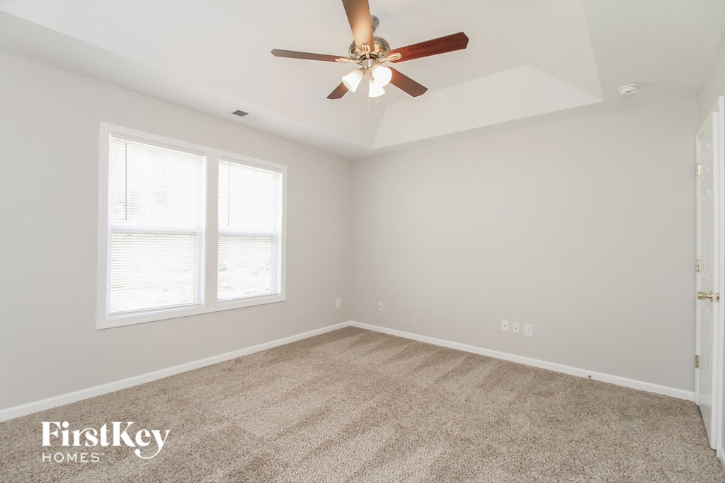 a bedroom with a ceiling fan and a carpet