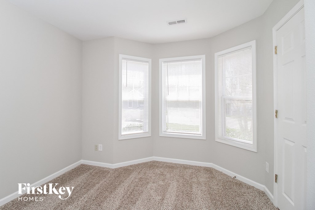 a bedroom with three windows and a carpeted floor