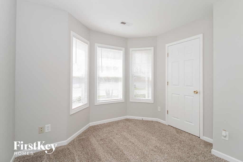 a bedroom with three windows and a white door