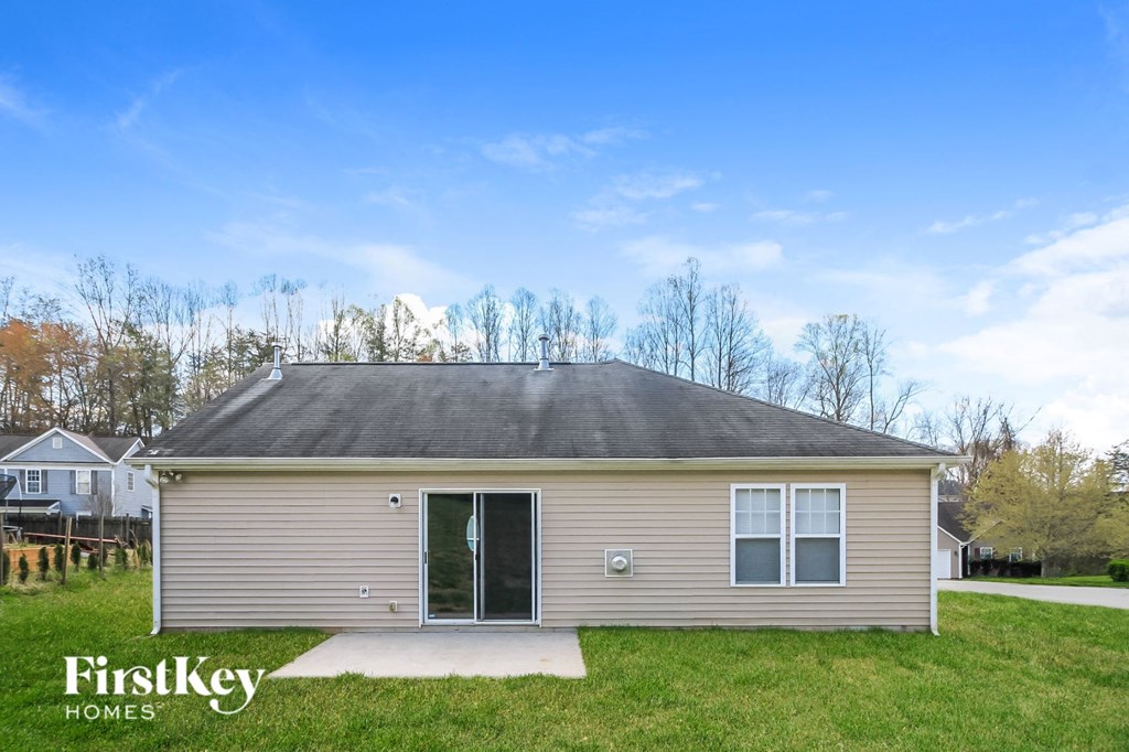 the exterior of a small tan house with a gray roof