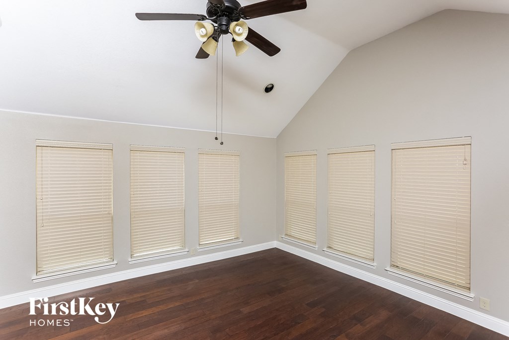 A room with a ceiling fan and wooden flooring.