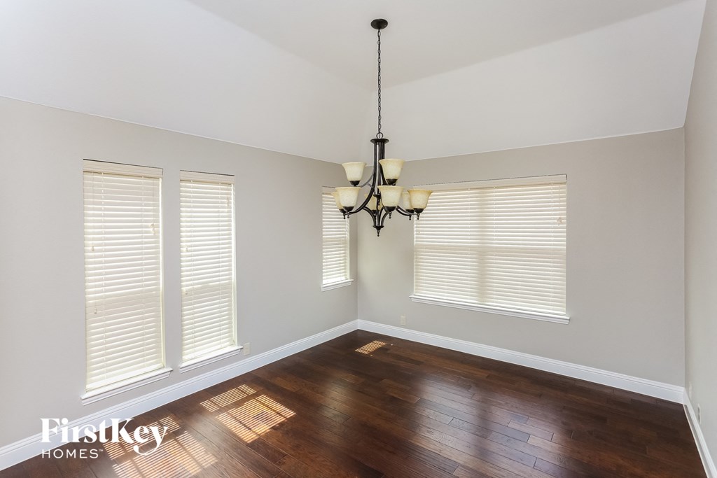 A room with wooden floors and a chandelier hanging from the ceiling.