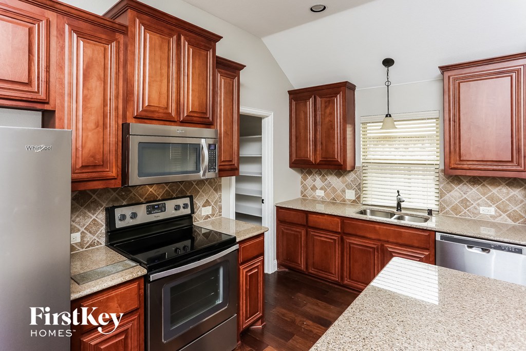 A kitchen with wooden cabinets and a stove top oven.