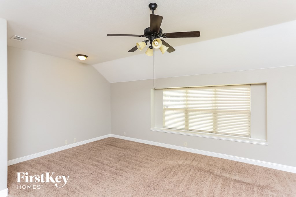 A room with a ceiling fan and a window with blinds.