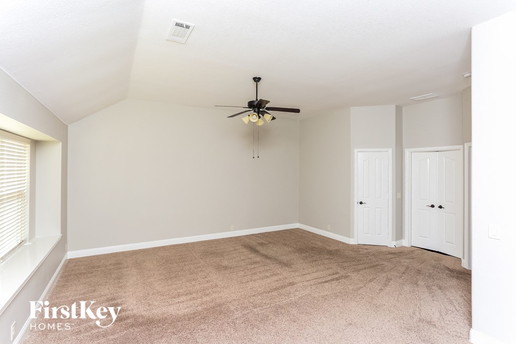 A room with a fan and carpeted floor.