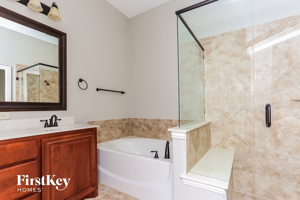 A bathroom with a white tub and a wooden vanity.