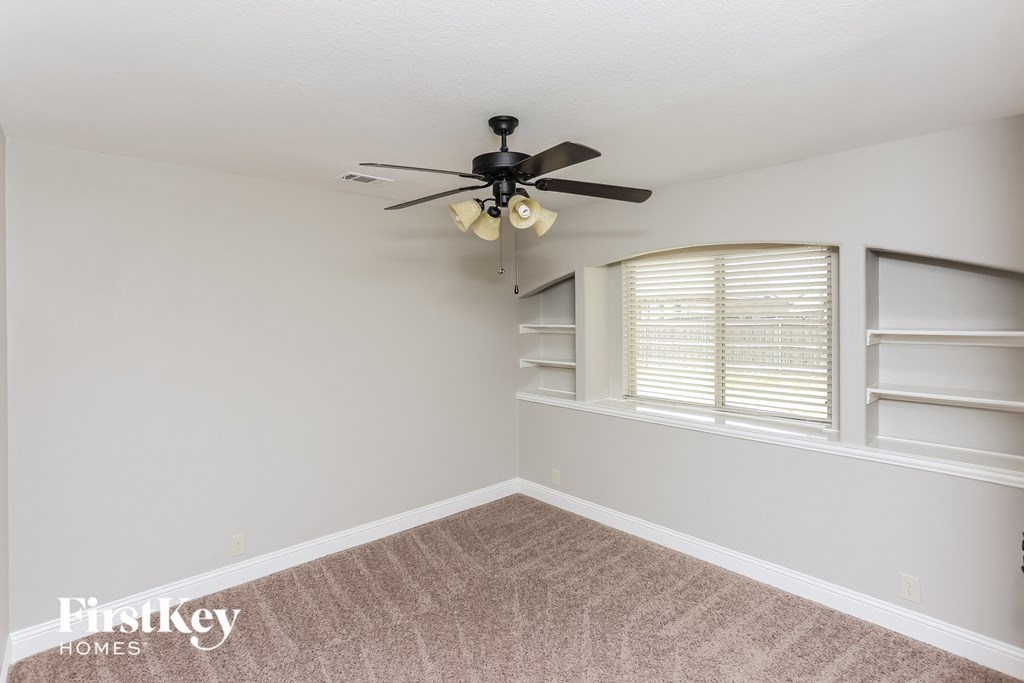 A room with a ceiling fan and a carpeted floor.