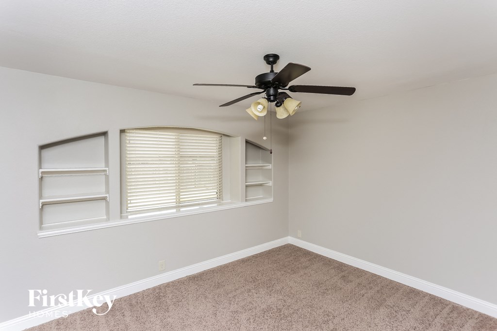 A room with a ceiling fan and two windows with blinds.