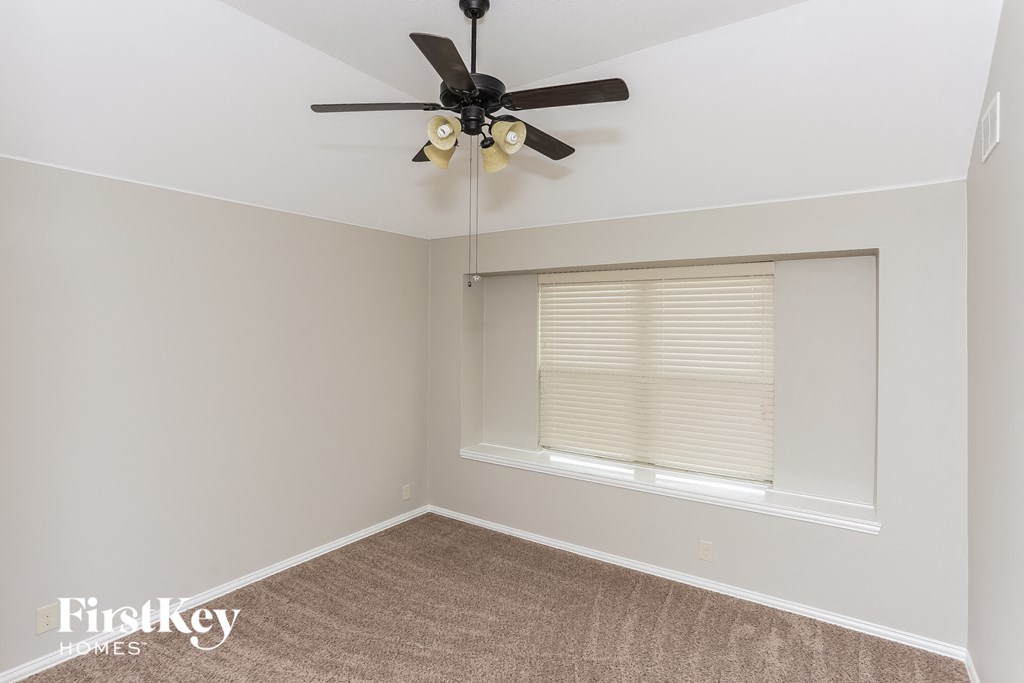 A room with a ceiling fan and a window with blinds.