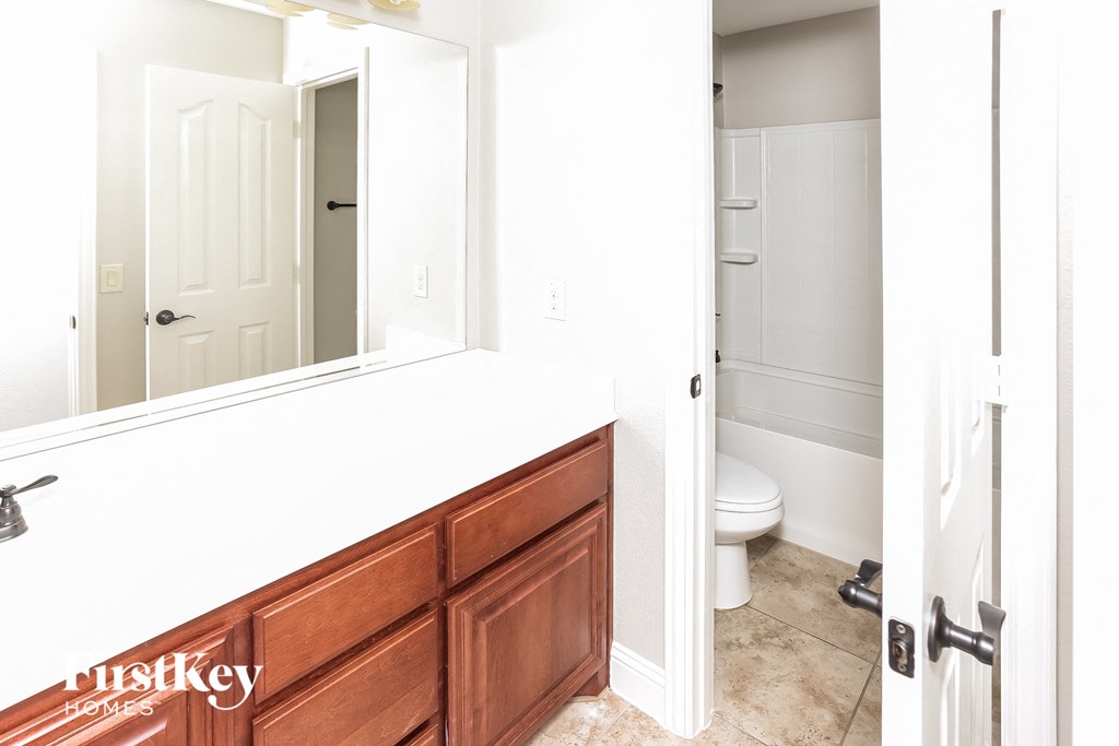 A white bathroom with a wooden vanity and a toilet.