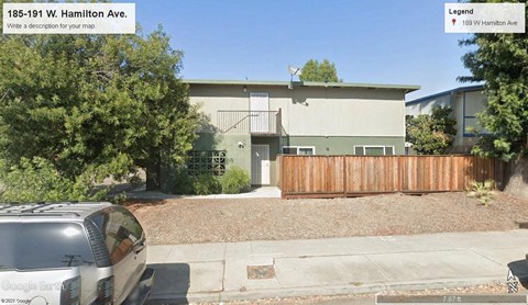 a car parked in front of a house with a wooden fence