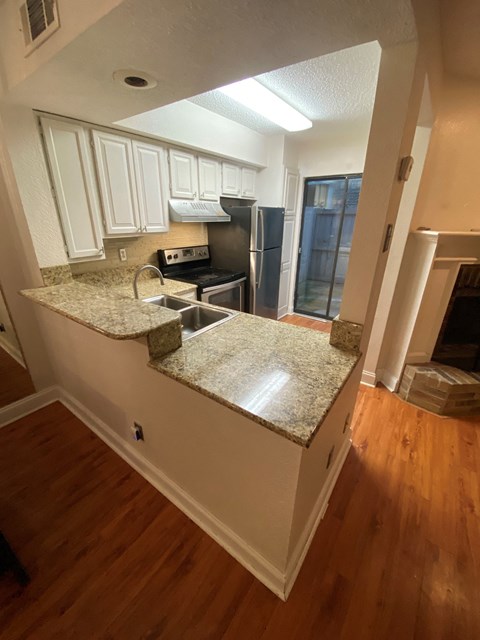 A kitchen with white cabinets and a granite countertop.