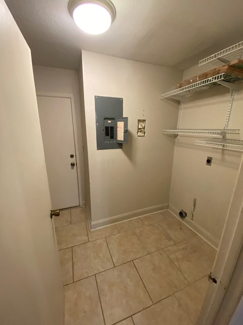 A hallway with a white door and a light switch on the wall.