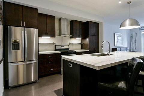 A modern kitchen with dark wood cabinets and a stainless steel refrigerator.