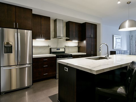 A modern kitchen with a stainless steel refrigerator and dark brown cabinets.
