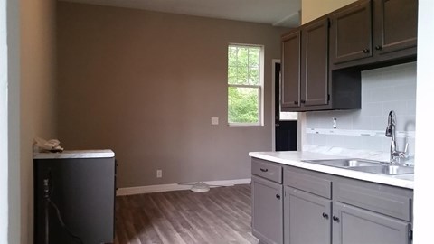 A kitchen with a white counter top and a window.