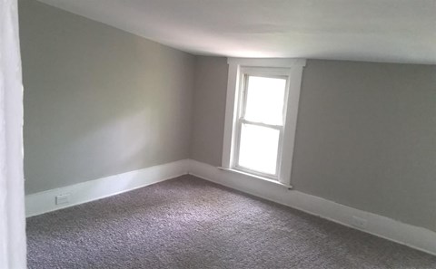 A room with a window and carpeted floor.