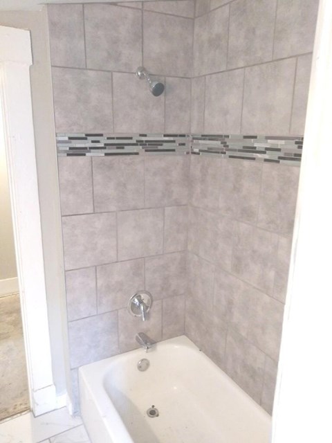 A white bathtub with a shower head and faucet.