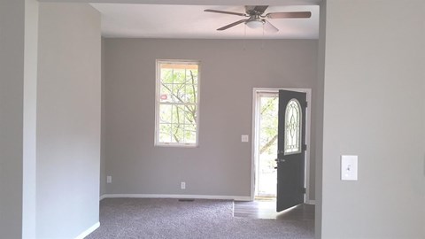 A room with a ceiling fan and a door.