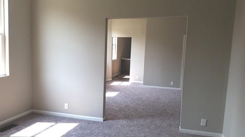 A room with a carpeted floor and a doorway leading to another room.