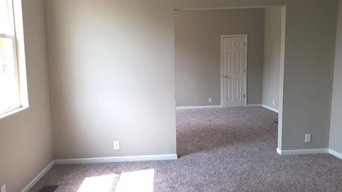 A room with a carpeted floor and two doors.