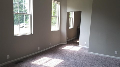 A room with two windows and a car parked outside.