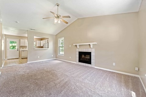 A living room with a fireplace and a ceiling fan.