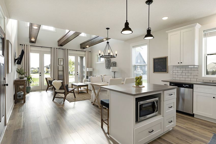 a kitchen with an island and a living room with a table and chairs