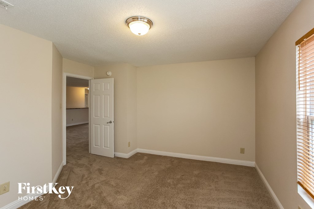 an empty living room with a door to the kitchen