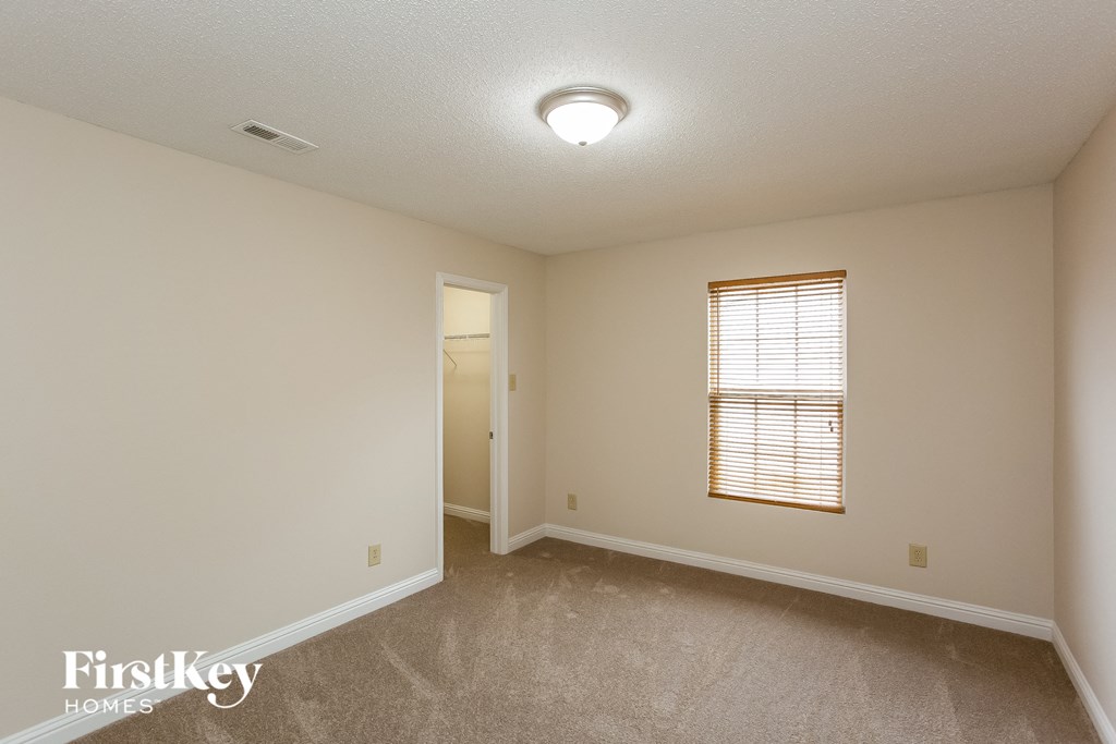 a spacious living room with white walls and a window