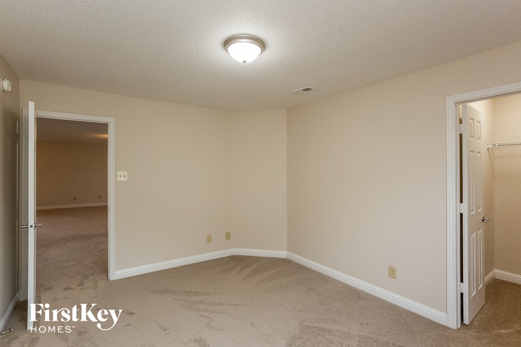 a bedroom with a door to a closet and a carpeted floor