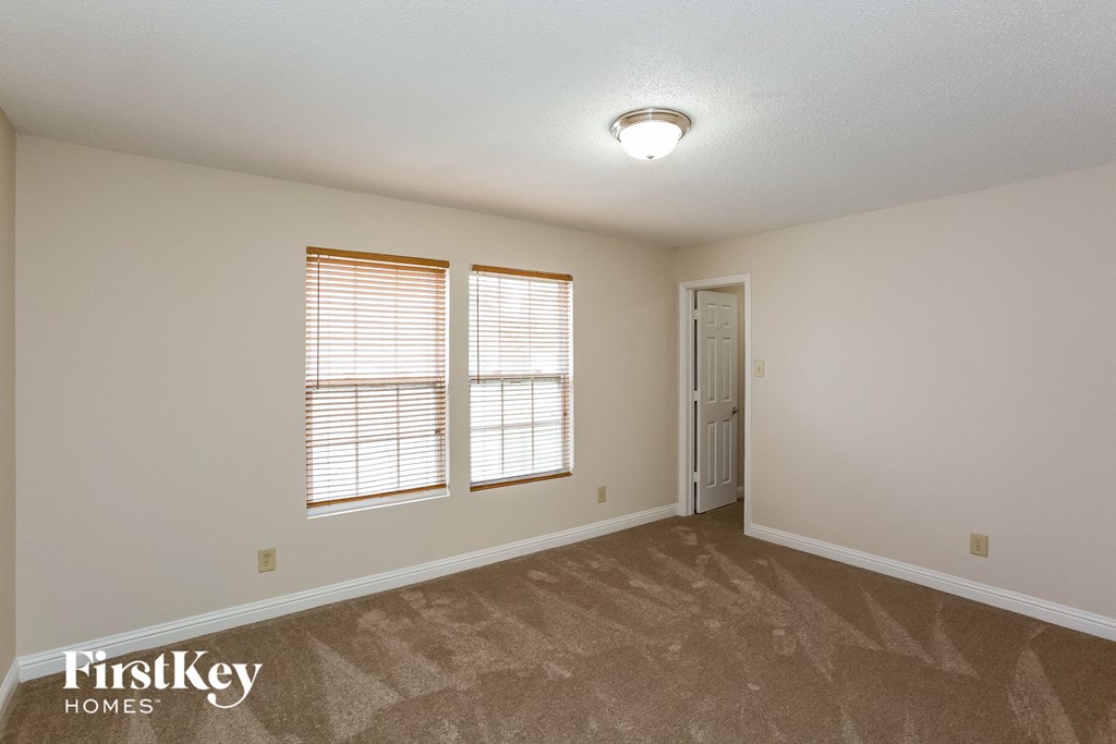 the spacious living room with two windows and a door to the hallway