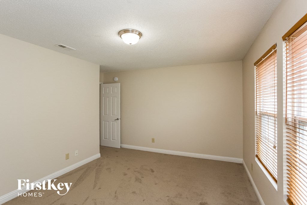 a spacious living room with two windows and a white door
