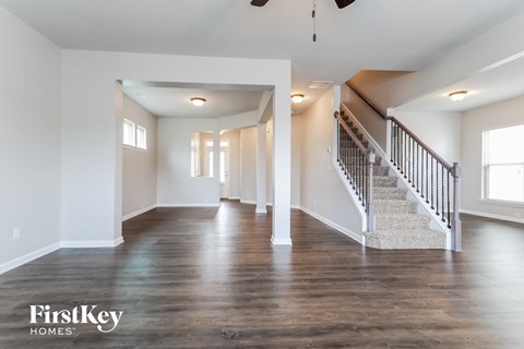 the family room and staircase of a new home with white walls and wood floors