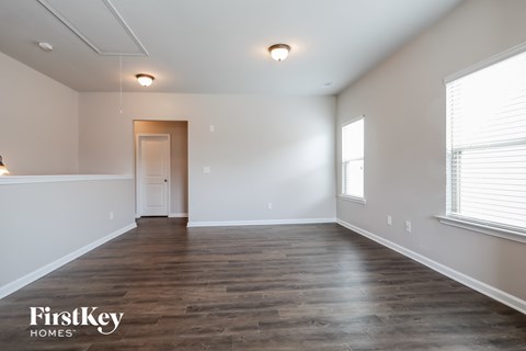 the spacious living room with wood flooring and white walls