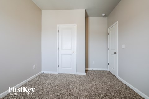 a bedroom with a white door and a carpeted floor