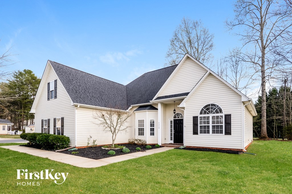 with white siding and black shutters on the front and a green lawn
