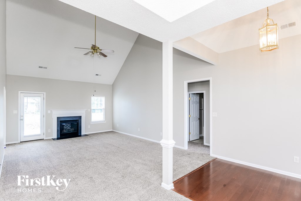 an empty living room with a fireplace and a ceiling fan