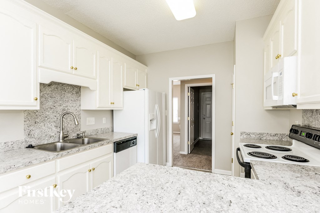 a kitchen with white cabinets and granite counter tops and a stove and refrigerator