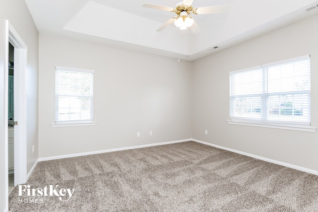 an empty room with carpet and a ceiling fan