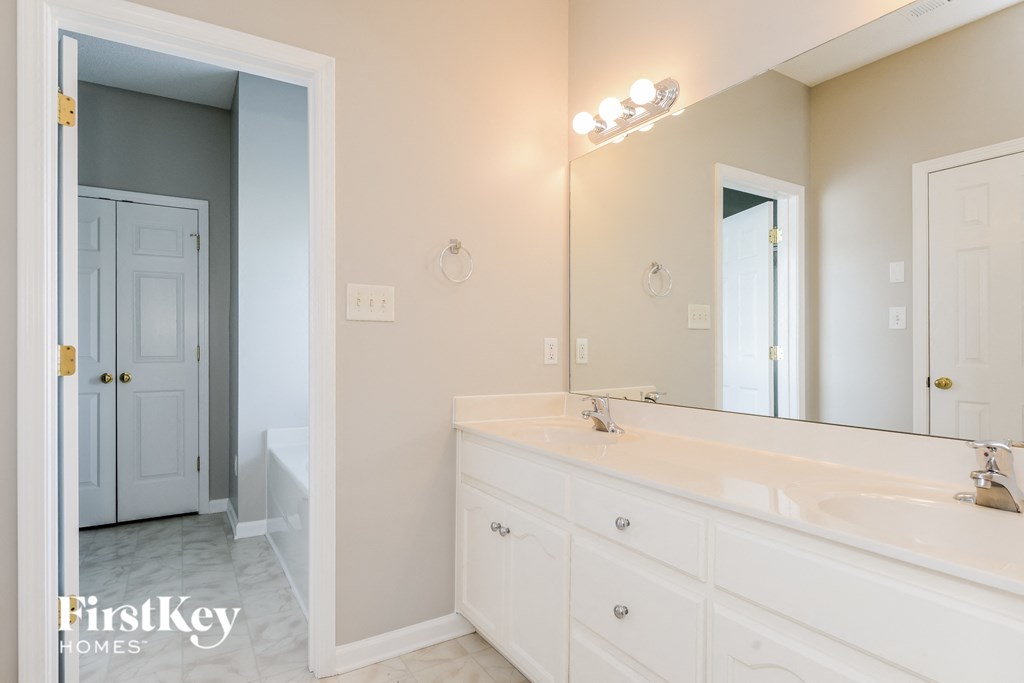 a white bathroom with a large mirror and a white sink